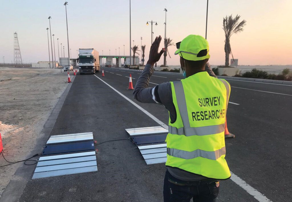 a man in a yellow vest is waving at a traffic light.