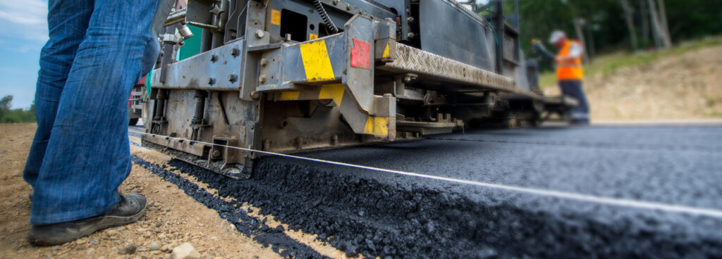 a man is laying asphalt on a road.