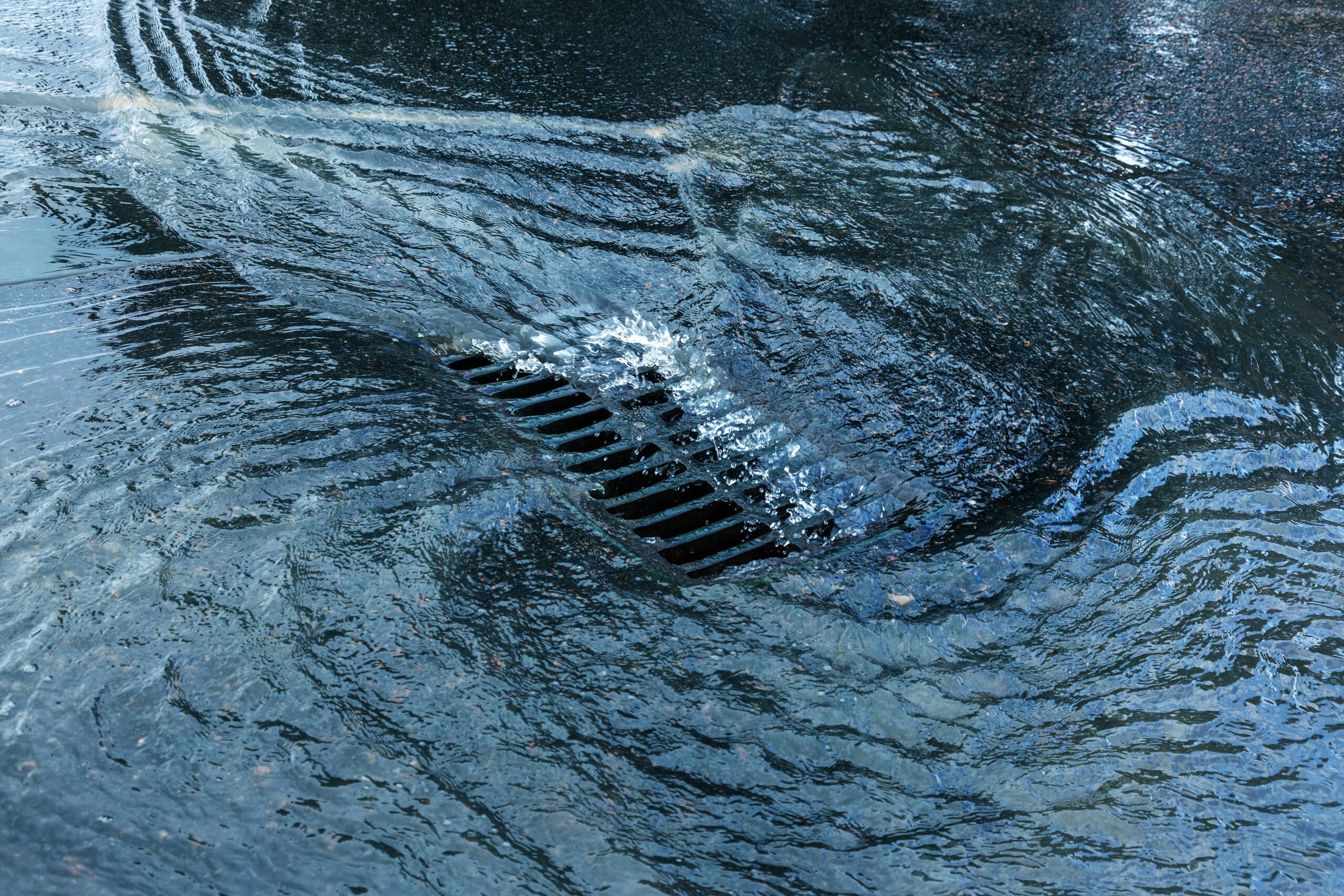 a flooded street with a grate in the water.
