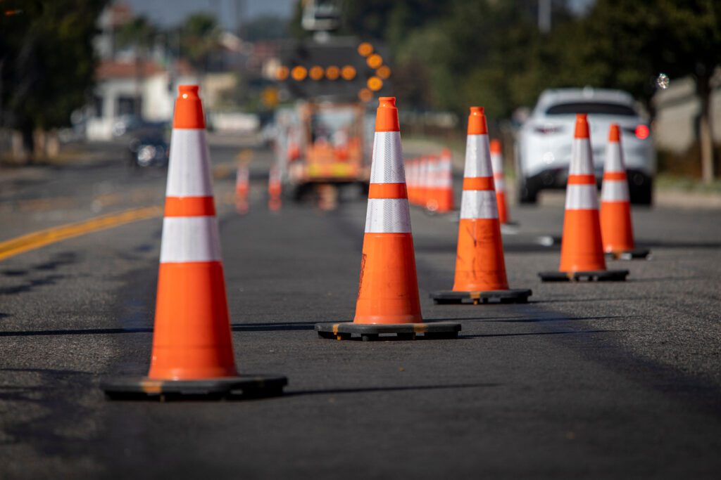 a group of orange and white cones on the side of a road.