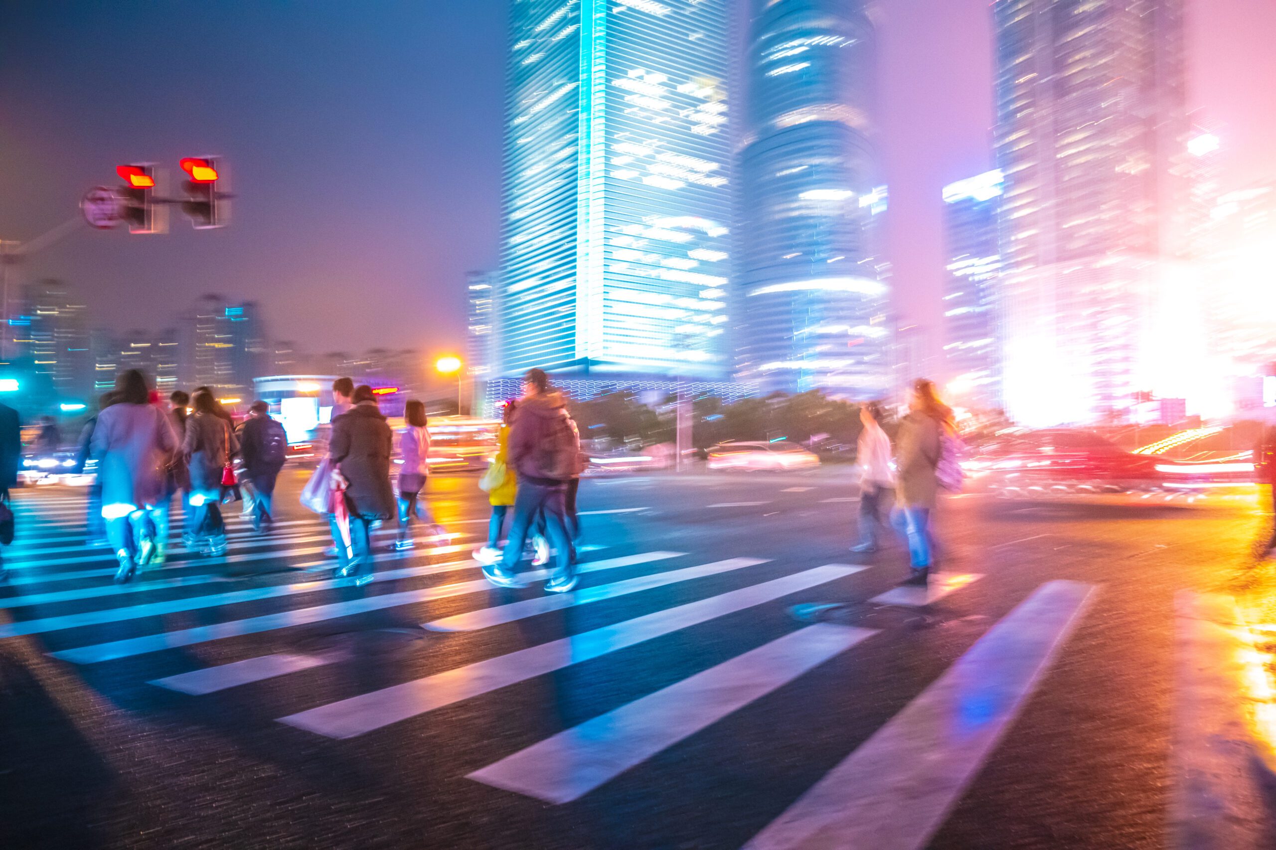 people crossing a street at night in shanghai.