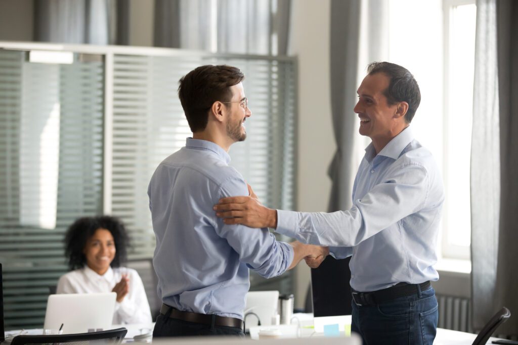 two businessmen shaking hands in an office.